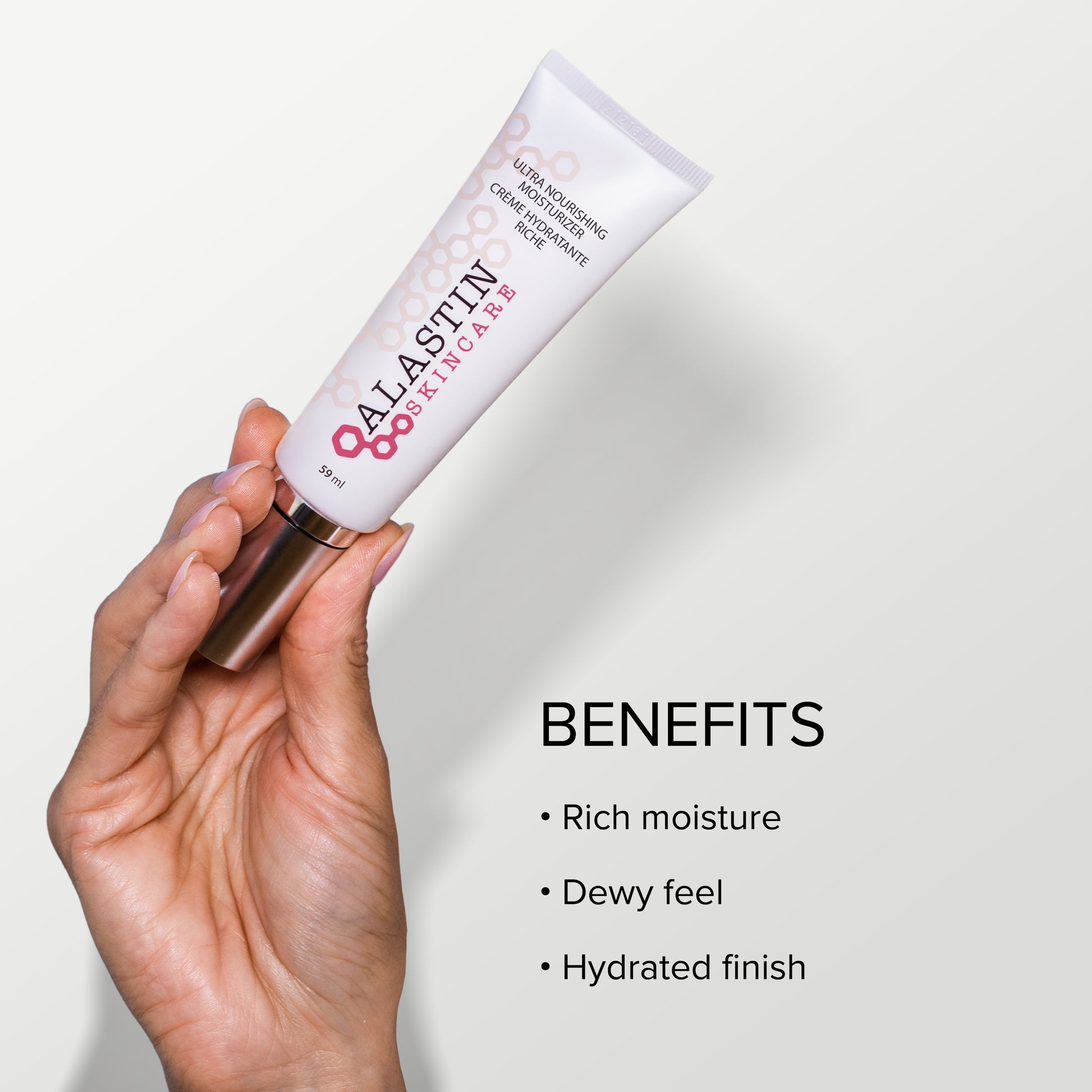 Hand holding a tube of Alastin skincare product with benefits listed on a light background